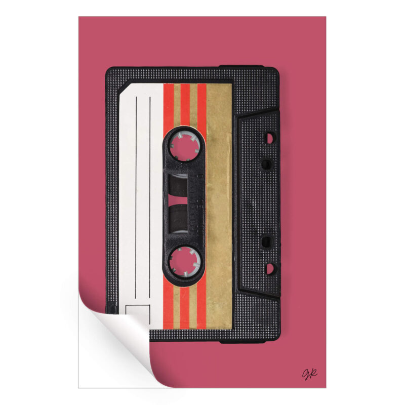 Black audio cassette tape with gold and red stripes on the label against a muted pink background.