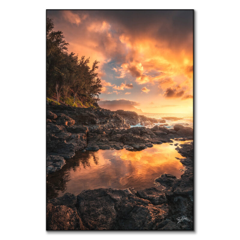 Sunset over the rugged coastline of Kauai, Hawaii, with fiery sky colors, volcanic rocks, and a tranquil tidal pool.