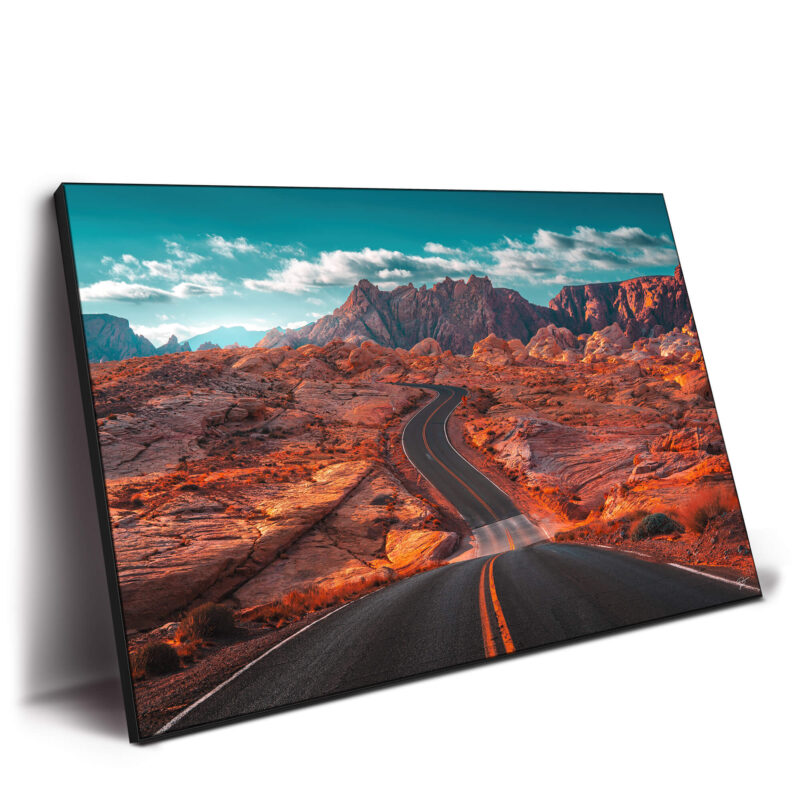 Winding road through the fiery red landscape of the Valley of Fire in Nevada, with rugged mountains and a turquoise sky.