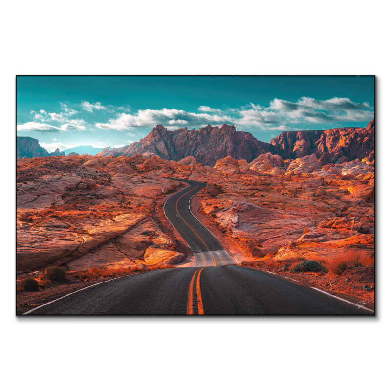 Winding road through the Valley of Fire in Nevada, with rugged mountains and a turquoise sky.