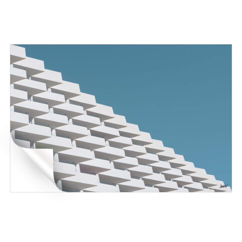 Geometric building facade with white angled balconies cascading against a blue sky.