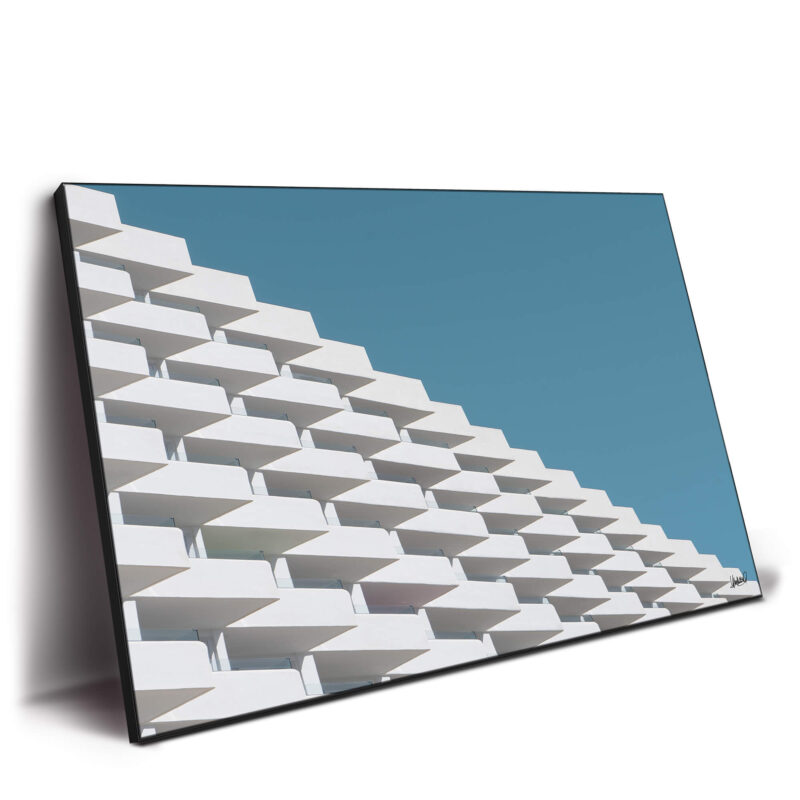 Geometric facade with white angled balconies cascading against a blue sky.