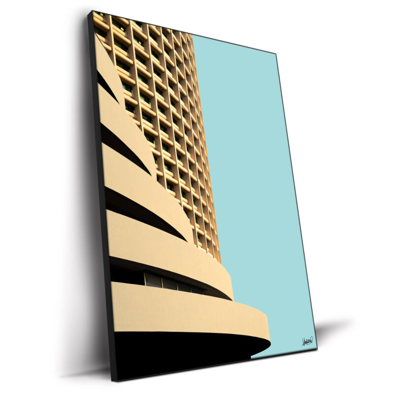 Tan curved high-rise building with repetitive windows against a pale blue sky.