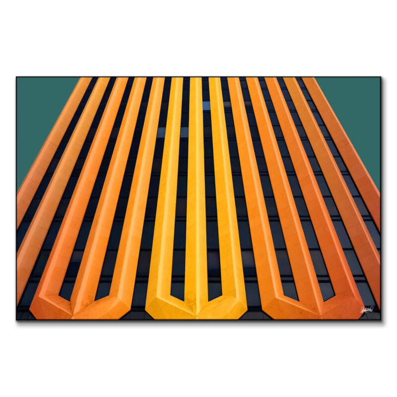 Building facade with vertical orange and yellow stripes against a green backdrop.