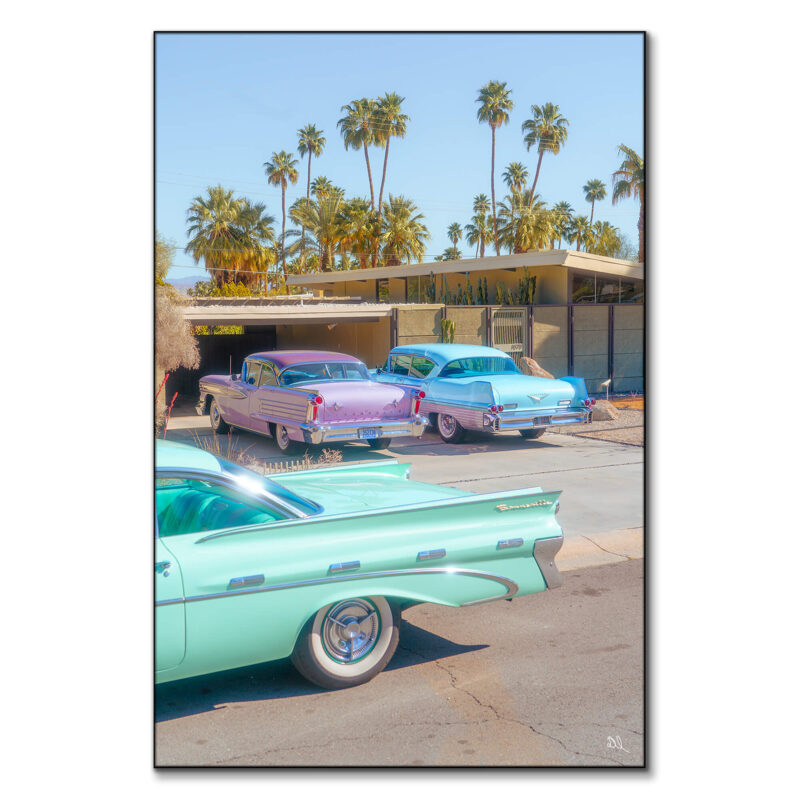Vintage cars parked in front of a mid-century modern house with palm trees in Palm Springs.