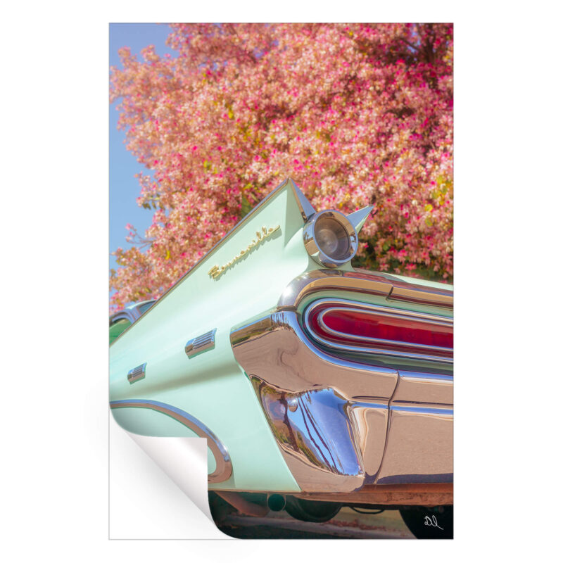 Classic green Pontiac Bonneville with chrome details against a blooming tree with pink flowers.