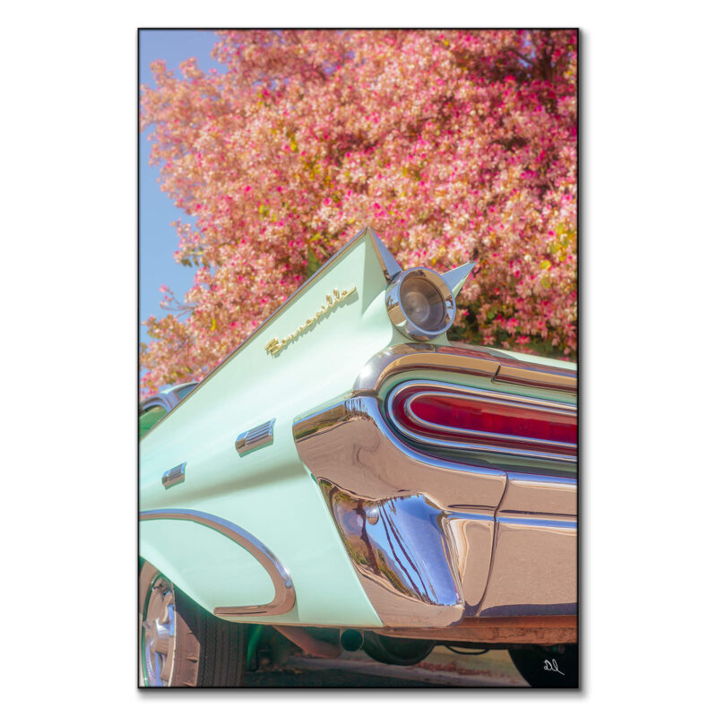 Vintage green Pontiac Bonneville with chrome details against a blooming tree with pink flowers.