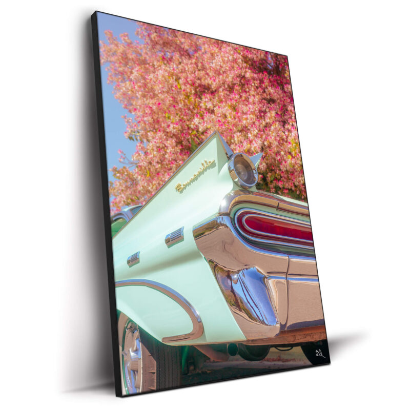 Vintage teal Pontiac Bonneville with chrome details against a blooming tree with pink flowers.