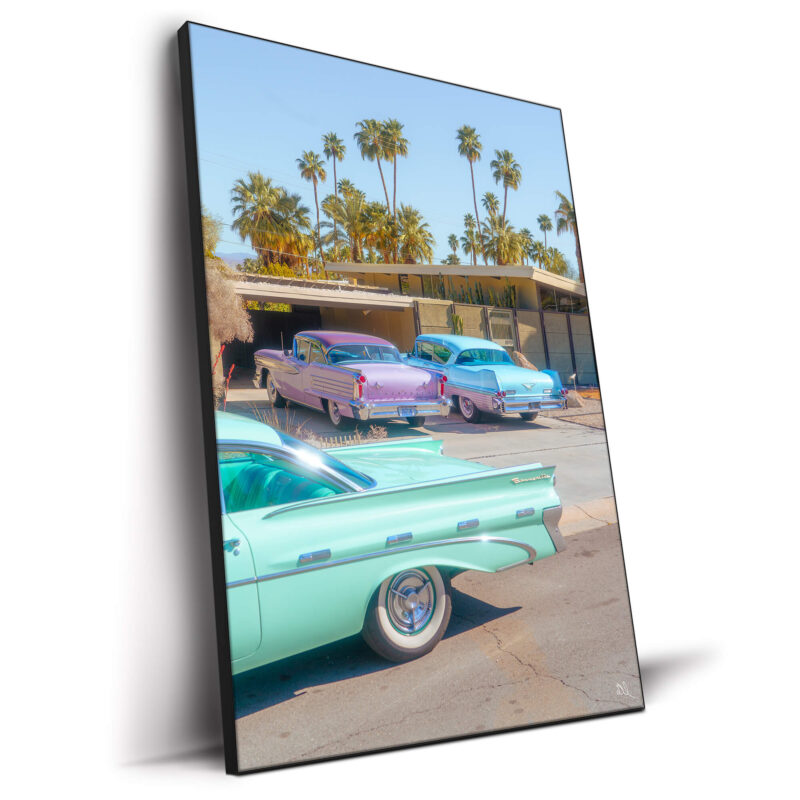 Pastel-colored vintage cars parked in front of a mid-century modern house with palm trees in Palm Springs.
