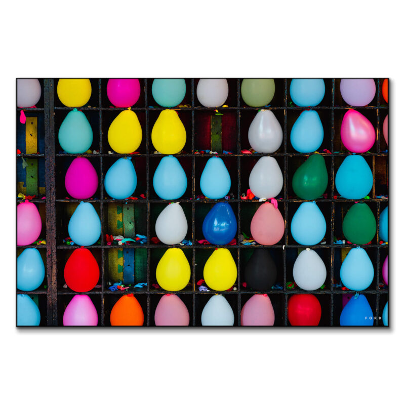 Colorful carnival balloons arranged in a game setup, showcasing a variety of bright colors against a blurred background.