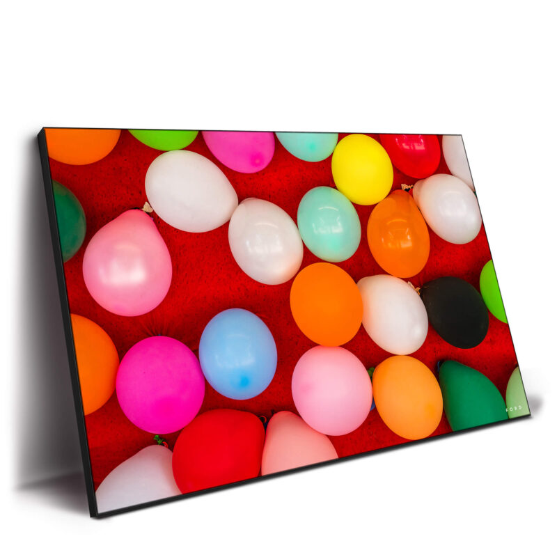 Assorted colorful party balloons scattered on a vibrant red background, creating a festive and playful atmosphere.