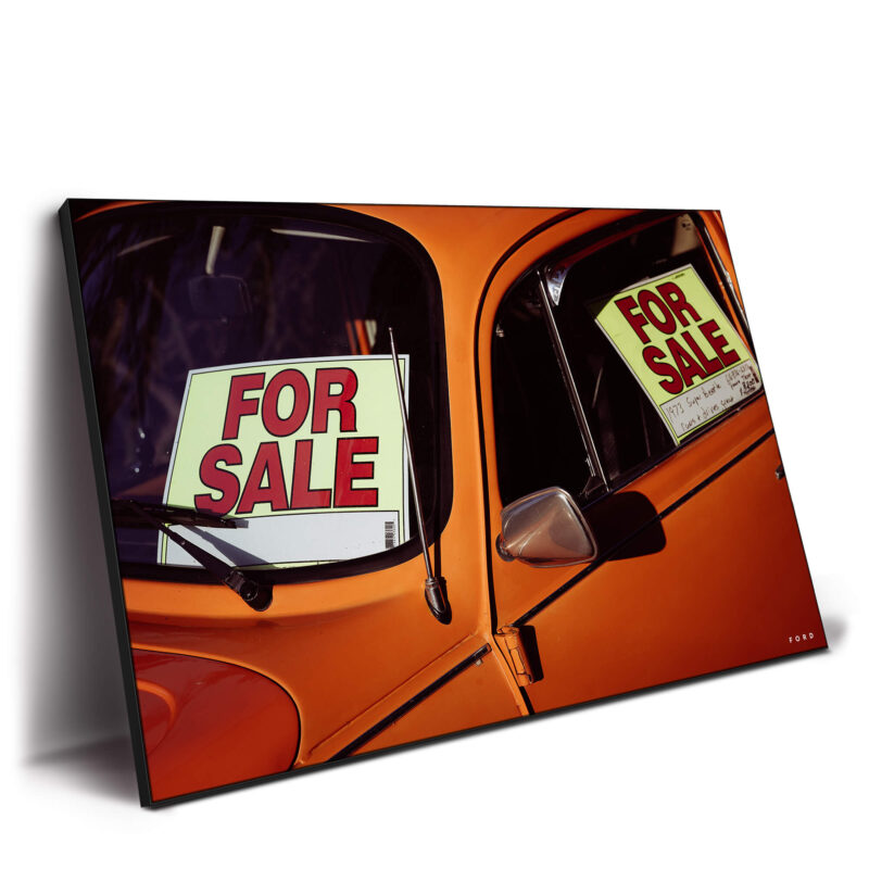 Vintage orange beetle car with 'For Sale' signs in the windows.