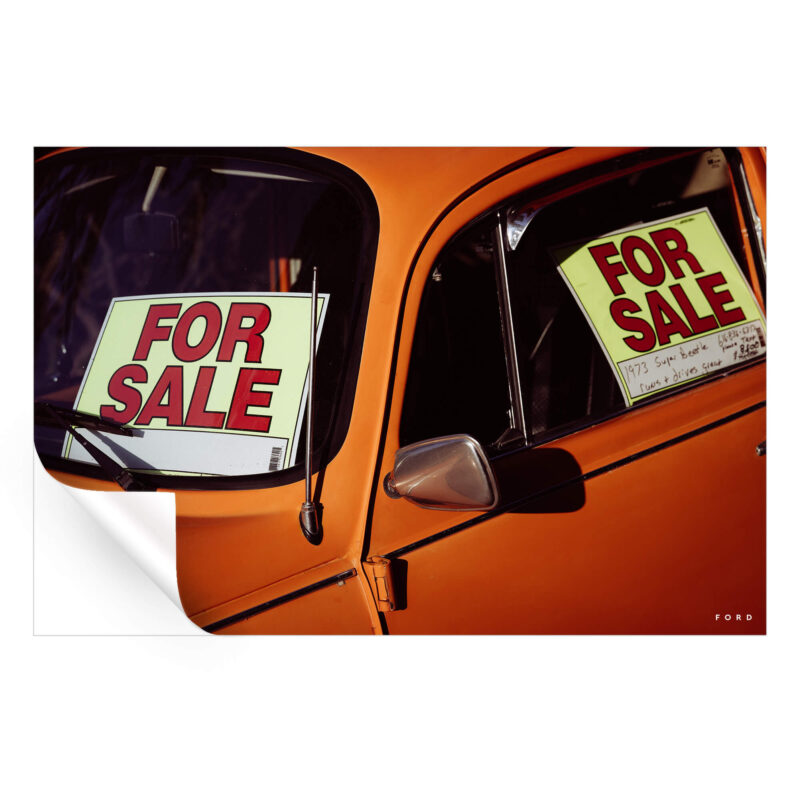 Vintage orange beetle car with 'For Sale' signs in the windows.