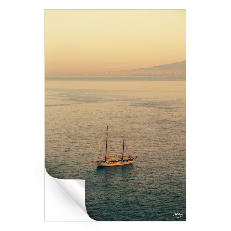 A sailboat on calm waters during a sunset in Italy.
