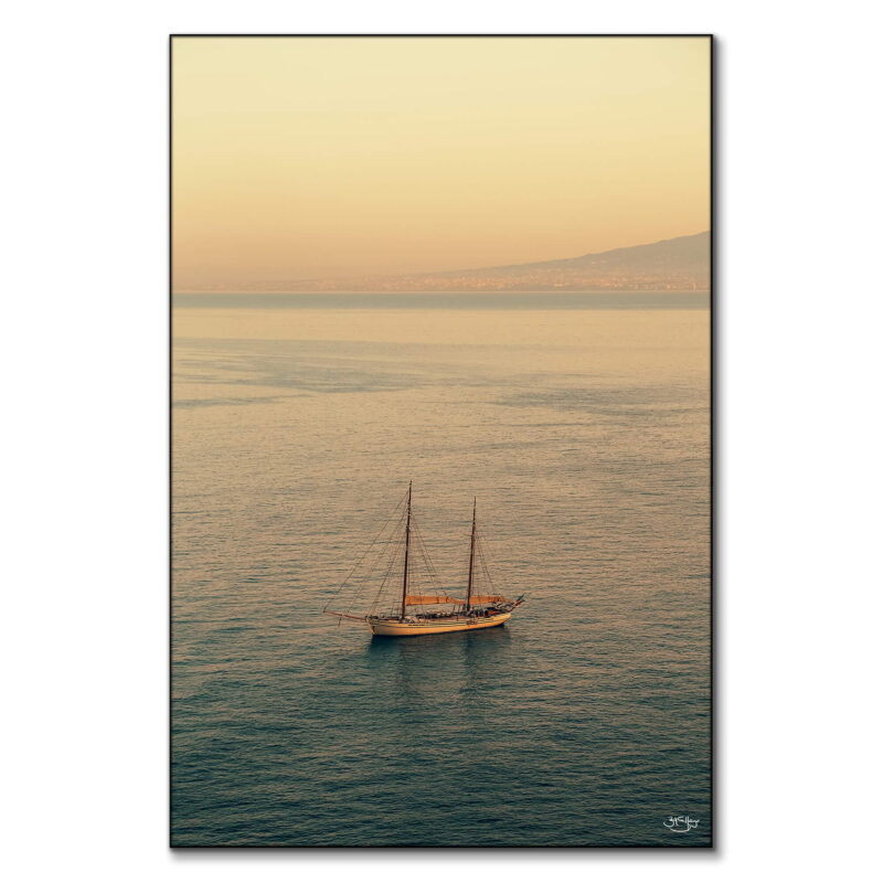 A sailboat on calm waters during a sunset in Italy.