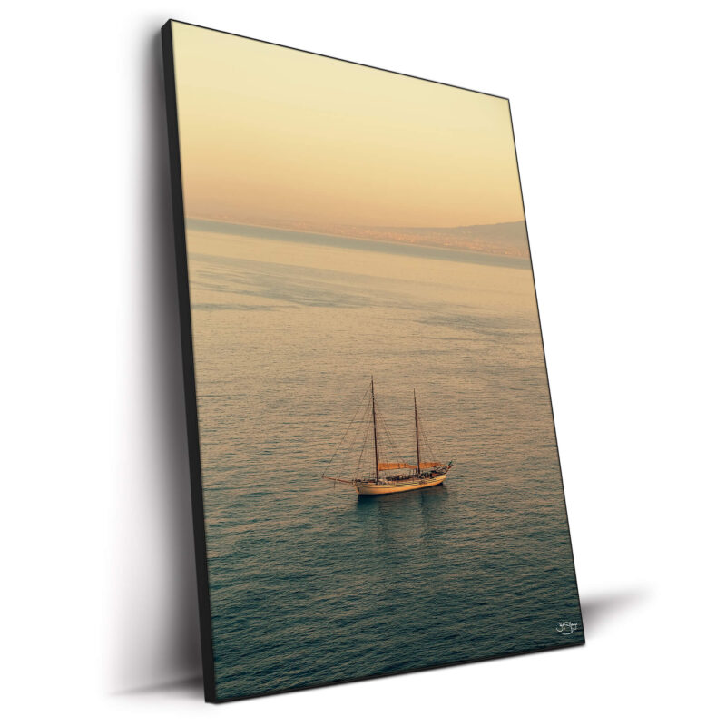 A sailboat on calm waters during a sunset in Italy.