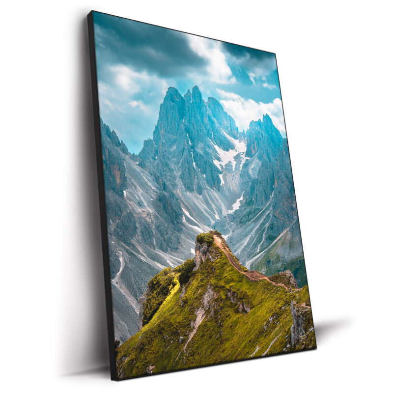 A person standing on a mountain peak, overlooking a vast and rugged landscape of valleys and peaks.