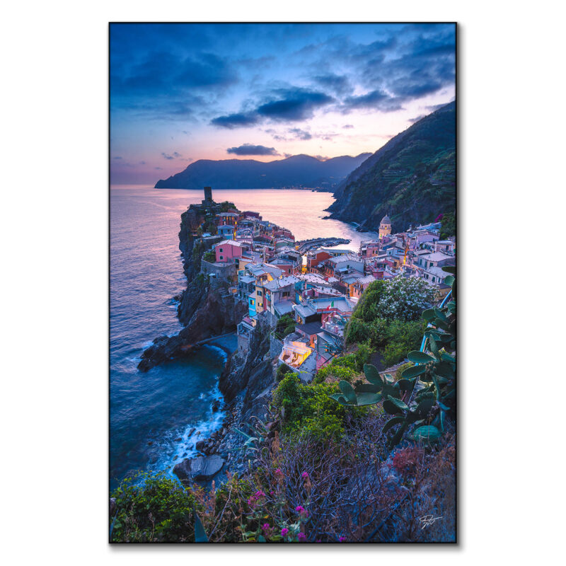 Vernazza village in Italy at sunset with colorful buildings by the sea.