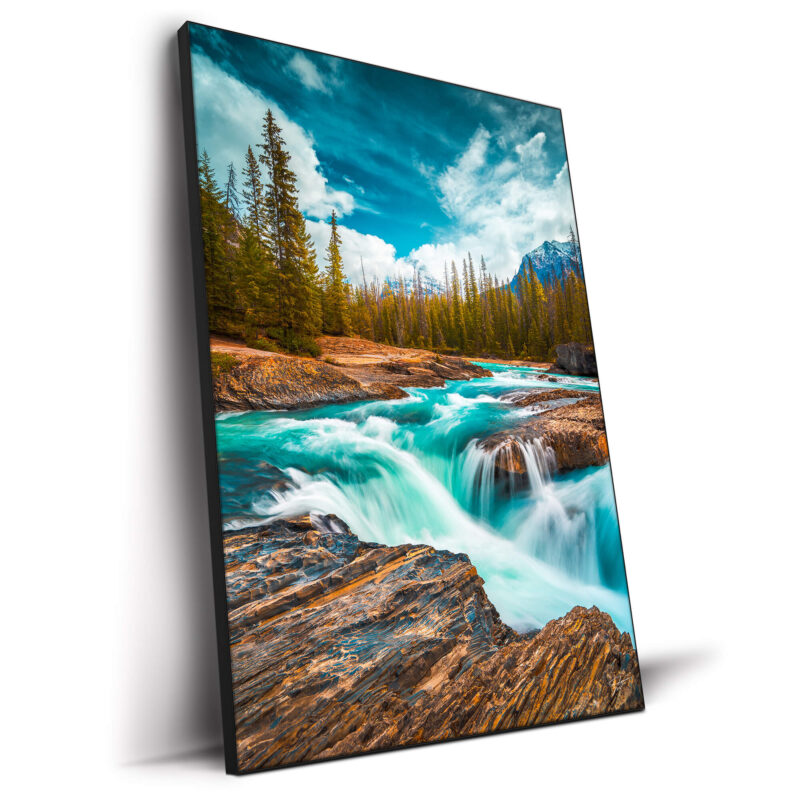 Rocky stream with aqua blue waters flowing over rocks, surrounded by trees and under a blue sky.