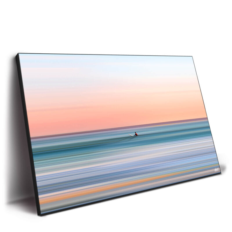 a surf boy riding a calm wave during a pink sunset